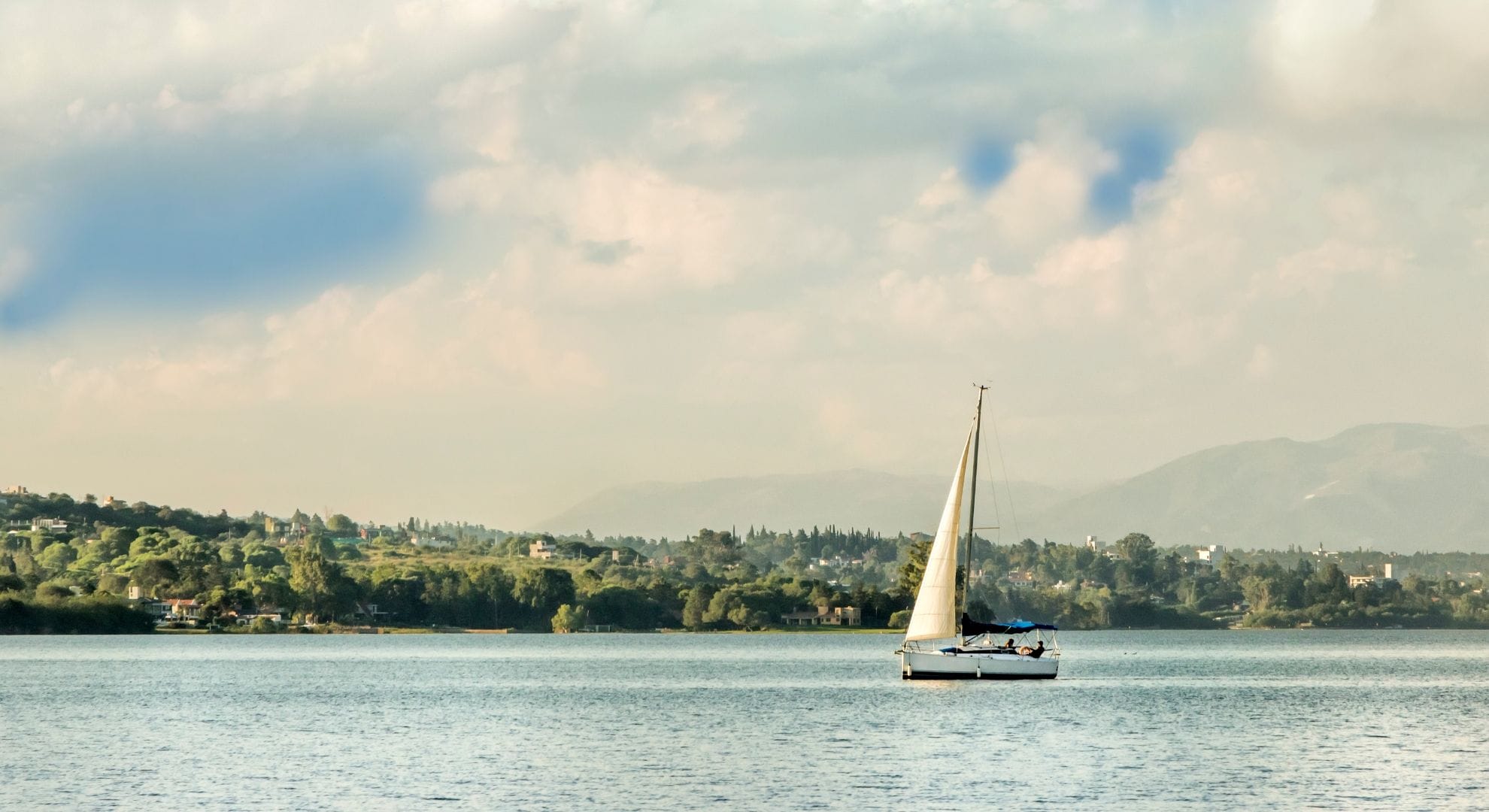 Velero en el lago San Roque frente a la costa de Villa Carlos Paz, con las sierras de fondo